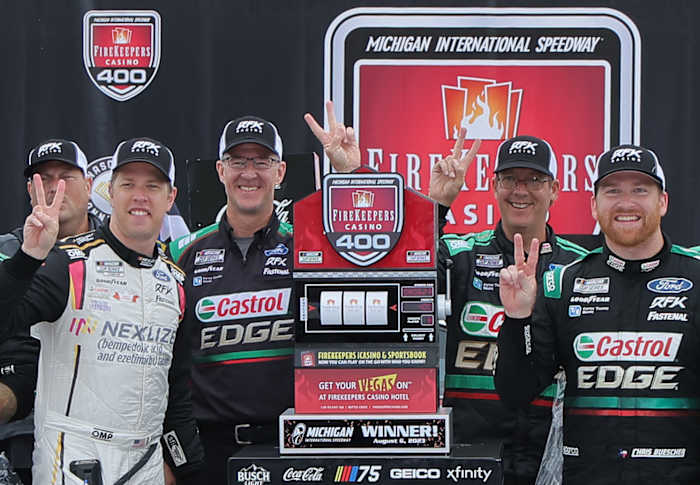 Chris Buescher celebrates with RFK Racing co-owner Brad Keselowski and crew chief Scott Graves after winning the NASCAR Cup Series FireKeepers Casino 400 at Michigan International Speedway. (Photo by Jonathan Bachman/Getty Images)